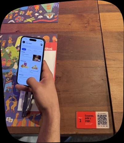 Un cliente paga con el celular en la mesa, junto al QR de CheckCheckCheck